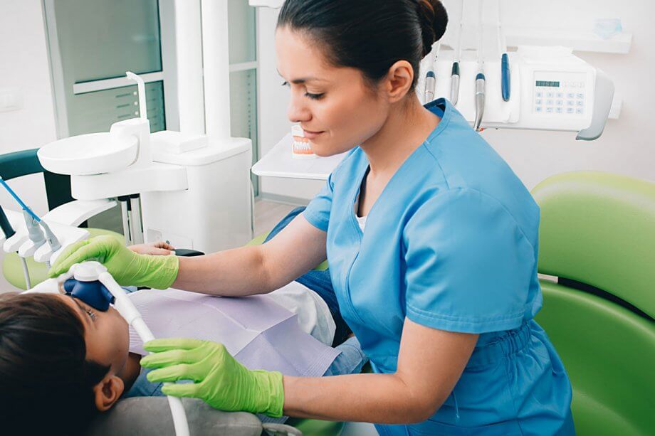 dental assistant providing sedation to boy in dental chair