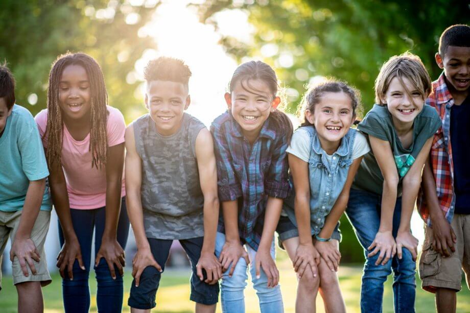 group of elementary school kids standing next to each other outside with hands on knees