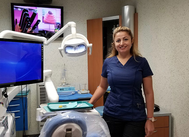 dental assistant standing next to exam chair