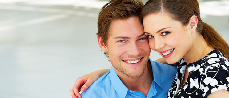 young couple sitting close to each other smiling toward camera