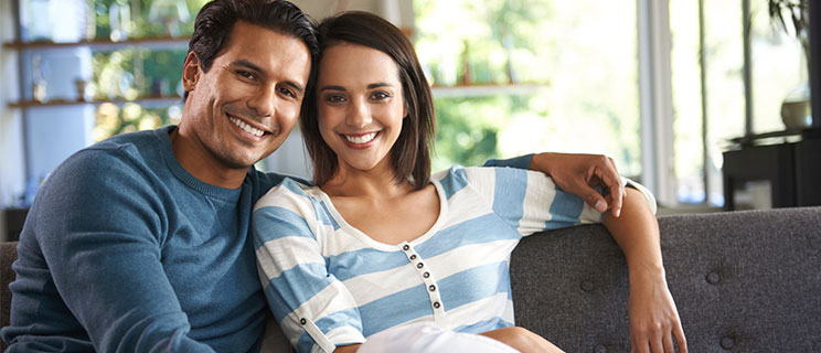 young couple sitting on couch, smiling toward camera