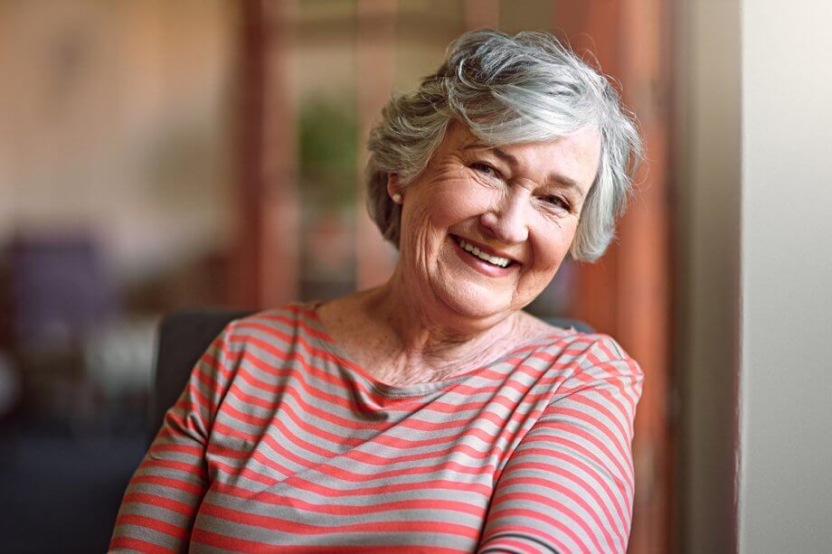 older woman in striped shirt facing the camera, smiling